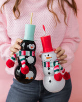 Woman holding Penguin and Snowman sipper shot against pink background. 