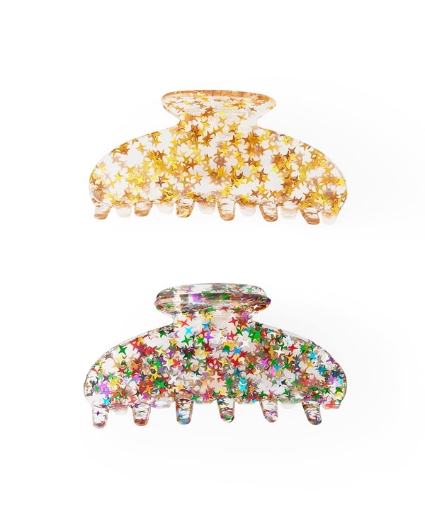 Two claw clips lie against a white background. The claw clip on the top is clear with gold stars and the bottom one is clear with rainbow stars. 