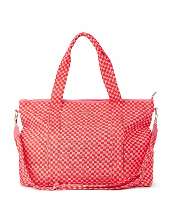 Large pink and red checkered duffel bag shot against white background