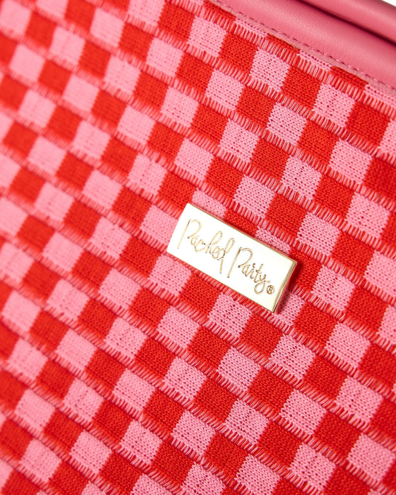 Close up shot of pink and red checkered pattern and gold hardware with the 'Packed Party' logo.