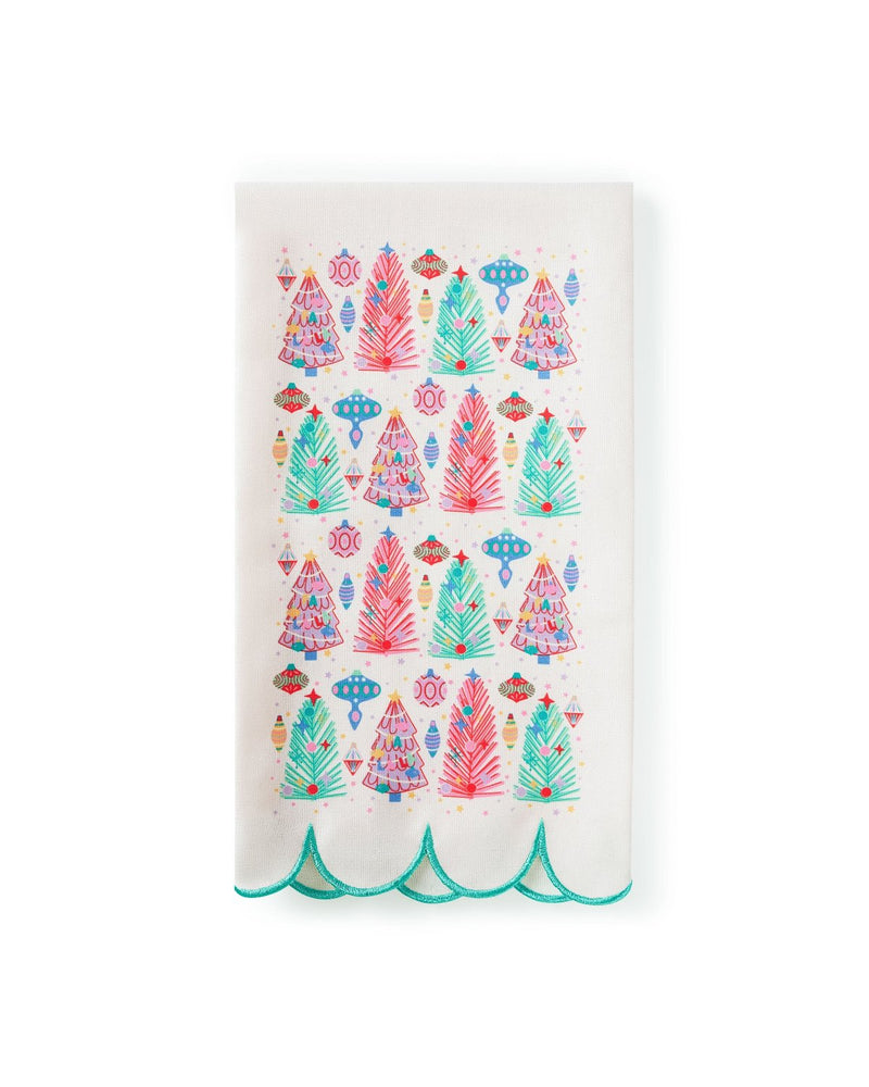 White tea towel with printed colorful Christmas trees and scalloped edge detail shot against white background. 