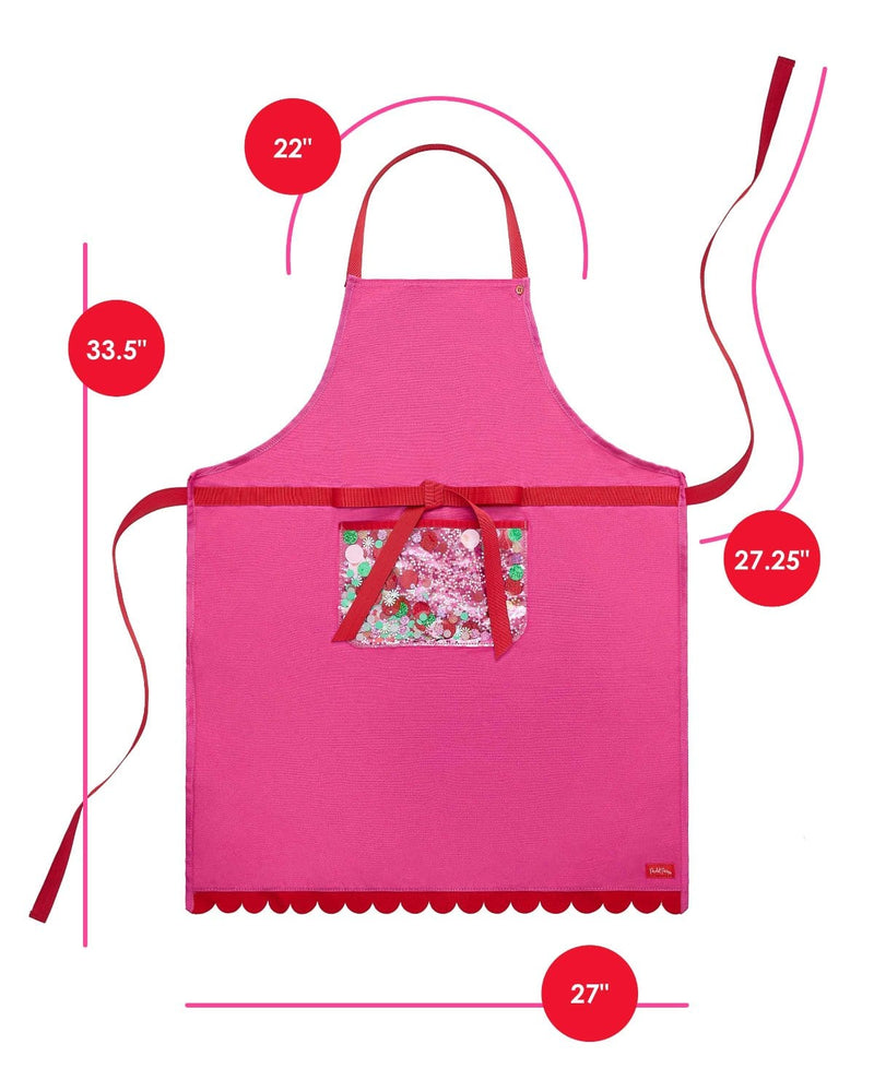 Pink apron with red scalloped edge, red trim details, and trapped confetti pocket shot against white background with dimensions . Height is 33.5", width is 27", length of side straps is 27.5", and length of neck strap is 22". 