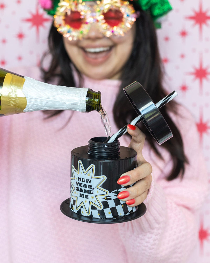 Woman pouring champagne into 'New Year, Same Me' Sipper with pink background. 