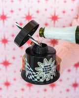 Champagne being poured into 'New Year, Same Me' Sipper shot against red and white patterned background. 