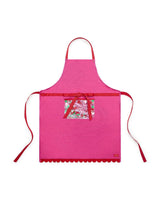 Pink apron with red bow across waist, red scalloped edge, and trapped confetti pocket shot against white background. 