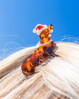 Santa dog claw clip placed in hair shot against the sky. 