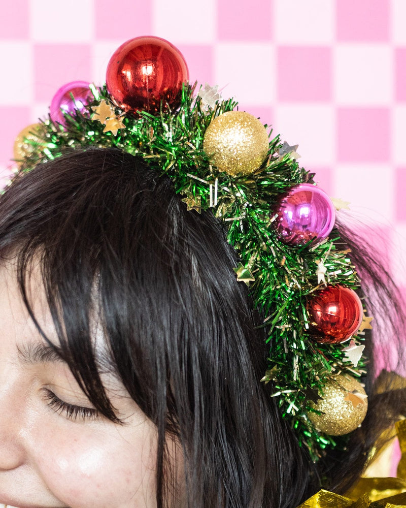 Close up of wreath headband worn on head shot against pink checkered background. 