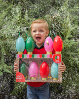 Child holding sipper set shot against background with greenery and snow. 