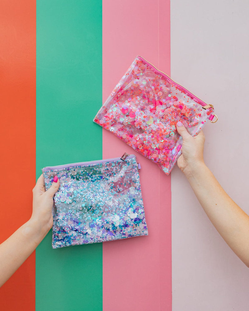 Two people hold two different pouches. On the left, one person holds a purple pouch while the person on the right holds a pink pouch.