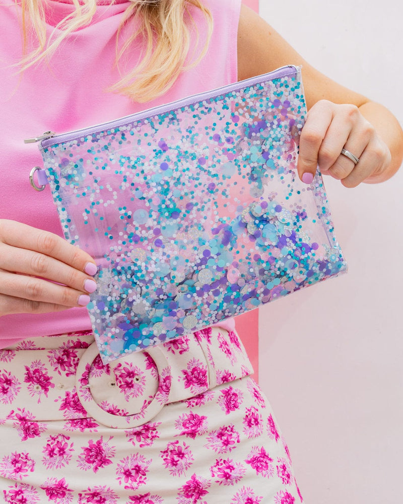 A person holds a clear vinyl pouch filled with purple confetti. 