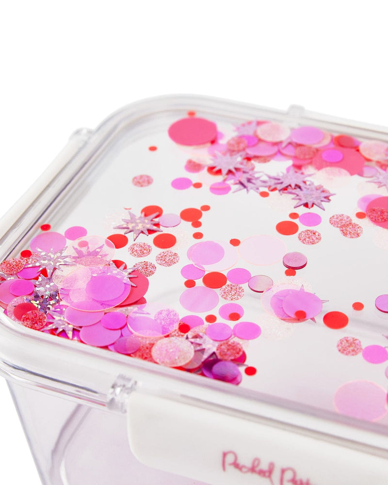 Close up view of clear plastic lunchbox lid with pink confetti trapped inside. 