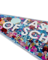 Close up view of pennant with multi-colored confetti trapped inside. The text that reads "Last Day of School" is partially obscured.