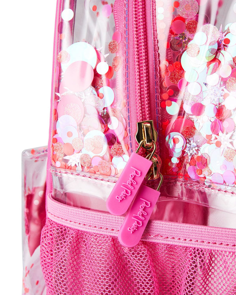 Close up shot of clear vinyl backpack with pink confetti. The shot is zoomed in and focuses on two pink zippers that read "Packed Party" in raised script. 