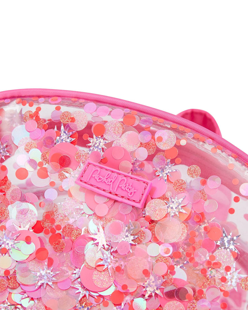 Close up shot of clear vinyl backpack with pink confetti. The shot is zoomed in and focuses on a pink label that reads "Packed Party" in raised script. 